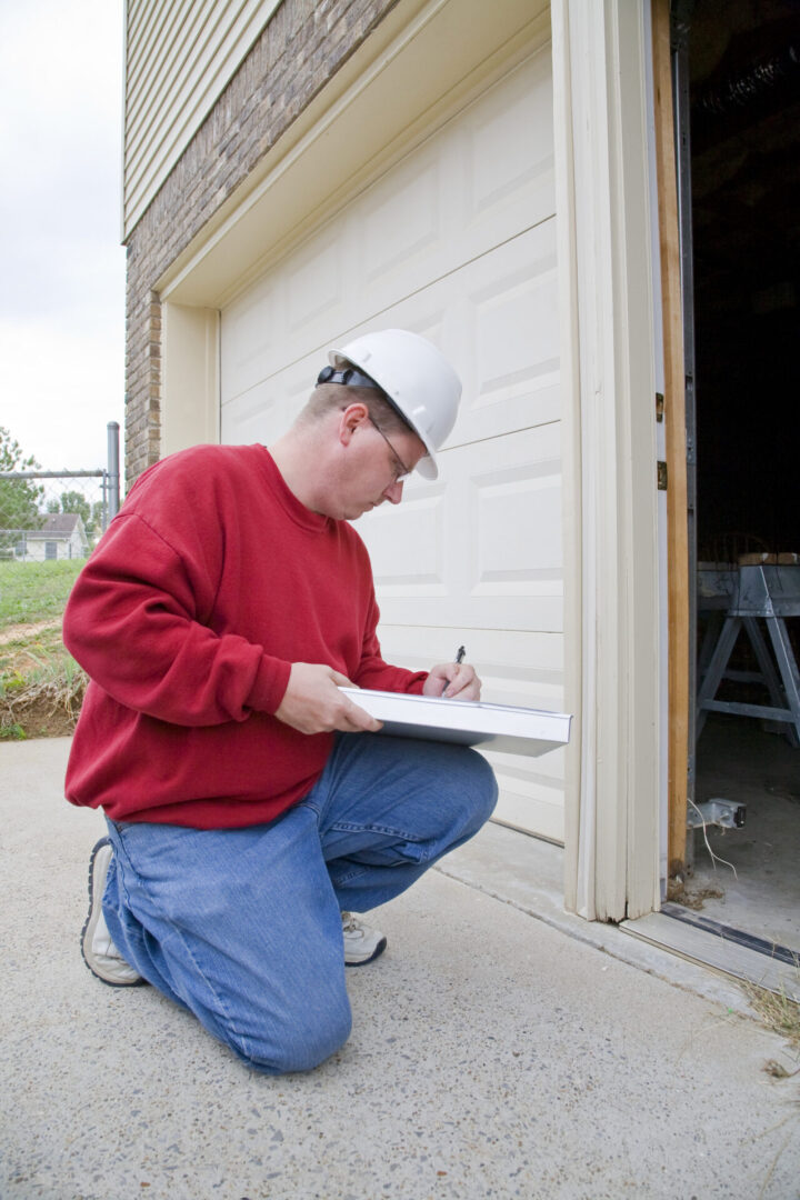 Inspector examining garage door, taking notes.