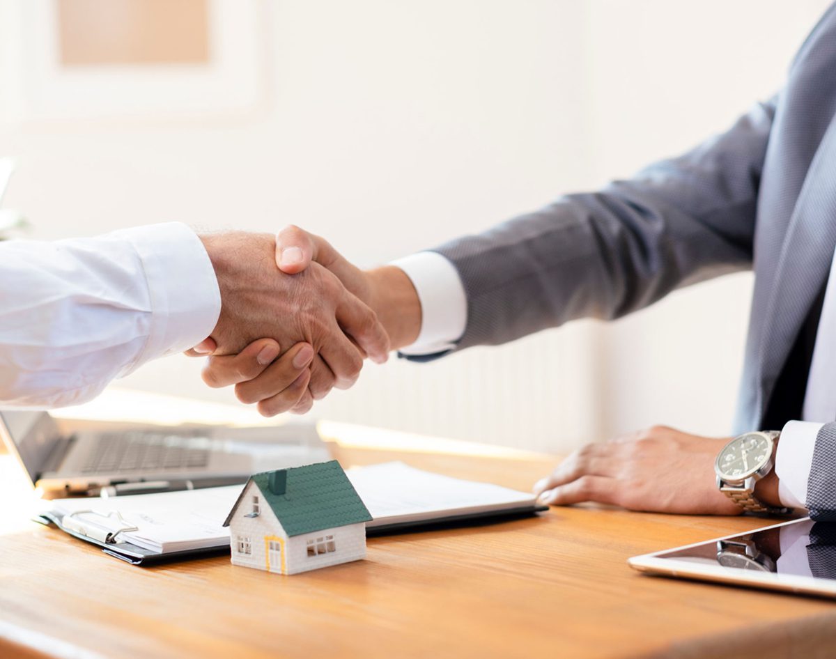 Handshake over a desk with documents.